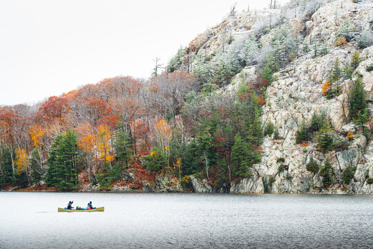Men Paddling Canoe across Northern Lake with Forest and Snowy Mountain