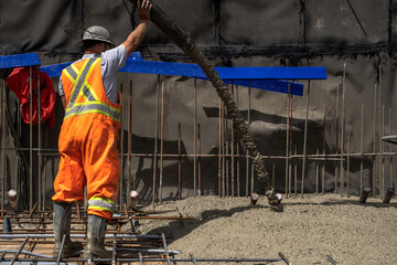 Worker in Protective Gear Pours Concrete