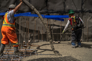 Construction Workers Pour Concrete Onto Rebar in Pit