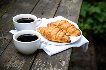 Coffee and croissants on old rustic wooden table