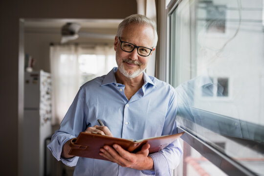 Man Wearing Glasses Writes Notes in His Notebook