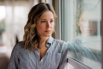 Serious Woman Leans Against and Looks Out a Window