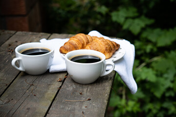Coffee and croissants on old rustic wooden table