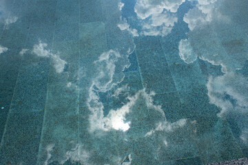 Abstract of sky reflection with  white clouds on green color calm water surface with sun light