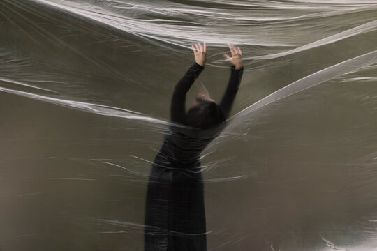 Young Woman Dancing In The Forest Through A Plastic Sheet