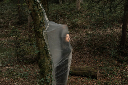 Young Woman Dancing In The Forest And Trapped In A Plastic Sheet
