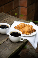 Coffee and croissants on old rustic wooden table