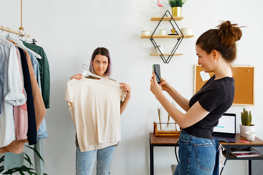 Young women taking photos of clothes at home