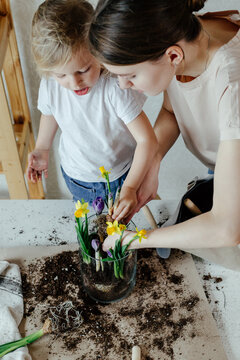 Mother and daughter planting flowers in glass pot