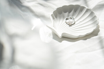 Engagement ring in shell-shaped jewelry plate on textured linen background