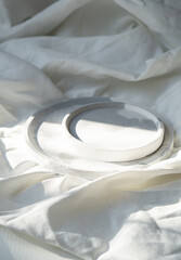 Obraz na płótnie Canvas Empty round tray on white textured linen background, designer jewelry plate