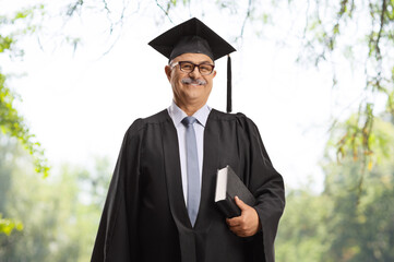 Mature man in a graduation gown holding a book