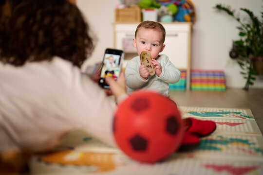 Babysitter taking photo on smartphone of baby.