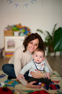 30`s brunette mother embracing pretty baby boy.