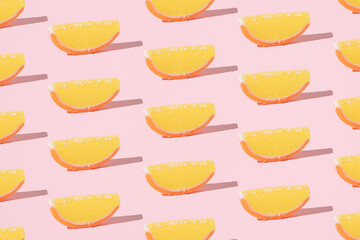 Orange jelly candies on a pink background. Minimal pattern.