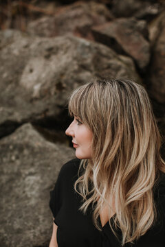 A Woman with Beautiful Blond Hair Looks to the Side with a Rocky Background