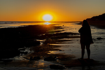 Woman from behind watching the sunset on a beach