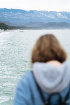 woman in blue jacket looking at the sea
