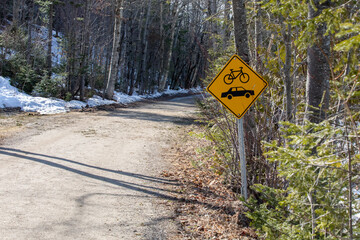 Pancarte jaune indiquant que les automobiles et les cyclistes doivent partager la route en campagne dans une forêt