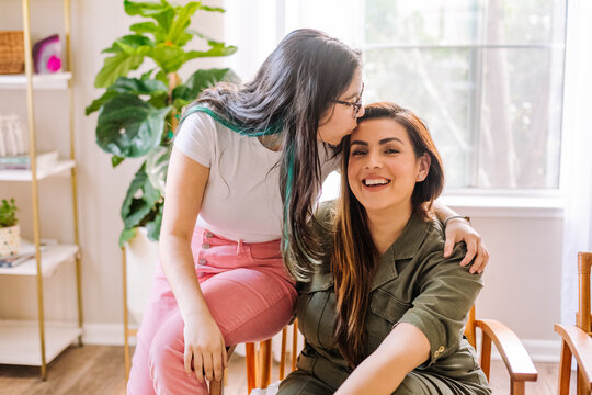 Teen kissing her Mother  on the forehead in living room