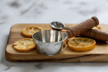 Tranches de citron séchées sur une planche à découper en bois avec une fraction d'une tasse à mesurer en métal avec manche en bois au look rustique avec lumière naturelle