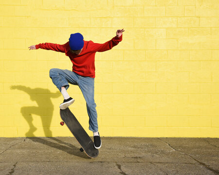 Cool Boy Skating Outside with Yellow Wall