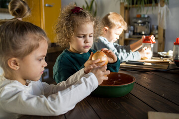 Two girls are peeling onions in the kitchen
