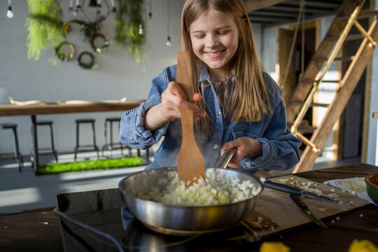 Little girl is frying  onions