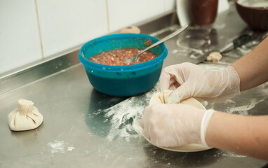 Fototapeta premium Female hands sculpt khinkali. Georgian food. Restaurant kitchen. 