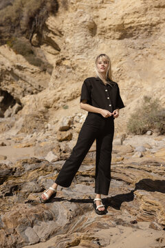 woman in black stylish set standing on rocky coast 