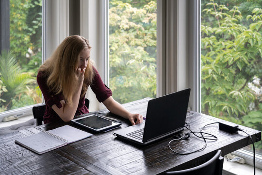 Teenage Girl Learning in Online Class at Home with Laptop Tablet and Paper Notebook