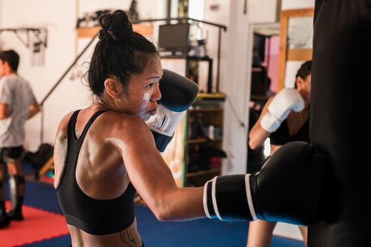 Thai Female Muay Thai Athlete Performing Hook On The Heavy Bag