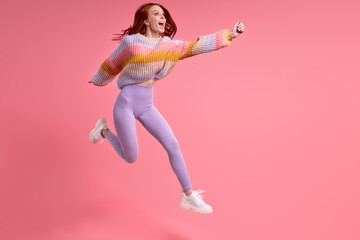 Fototapeta na wymiar Adorable cute funny woman jumping up in studio, caucasian lady raising hands forward, cheering, rejoicing. human emotions, people lifestyle concept