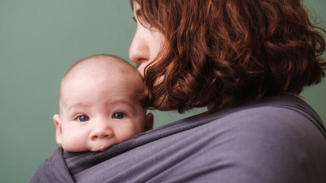Baby In A Wrap Carrier With His Mother