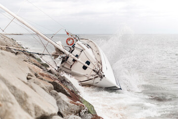 Wrecked sailboat at the coast with waves impact