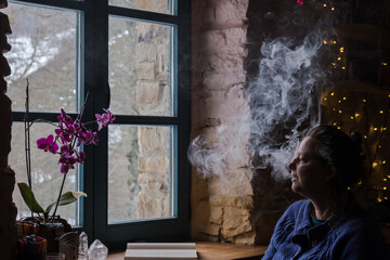woman smoking in front of a window 