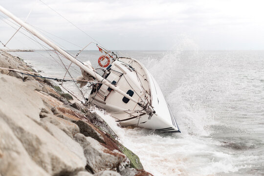 Wrecked sailboat at the coast with waves impact