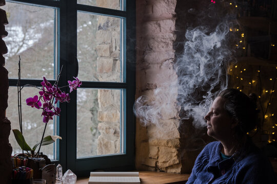 woman smoking in front of a window 