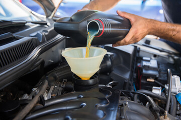 Car mechanic replacing and pouring fresh oil