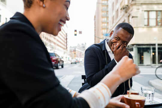 Friendly Coworkers Laugh Hard While Sipping Coffee at a City Cafe
