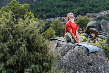 Middle aged man doing shoemaker pose asana in mountains 
