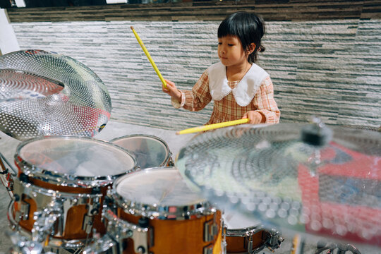 Little girl learning to play drums