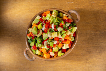 mixture of different vegetables cut into small cubes in rustic ceramic container on wooden table