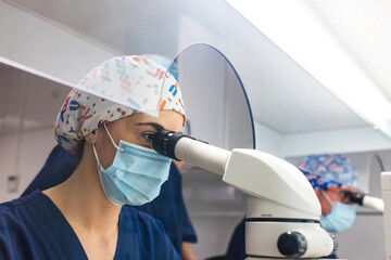 Biomedical scientist working with microscope in lab