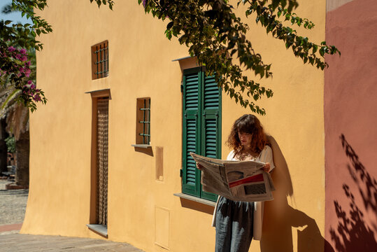 Woman leaning to a wall reading the newspaper