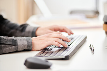 Crop male employee typing on computer keyboard