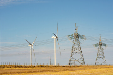 windmills electric power generators and high voltage distribution towers in a field