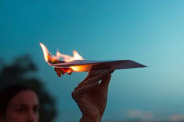Young woman holding a paper plane on fire