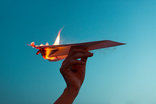 Holding a burning paper plane 