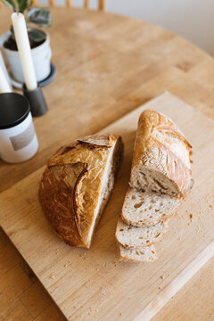Freshly baked sour dough sits sliced on cutting board